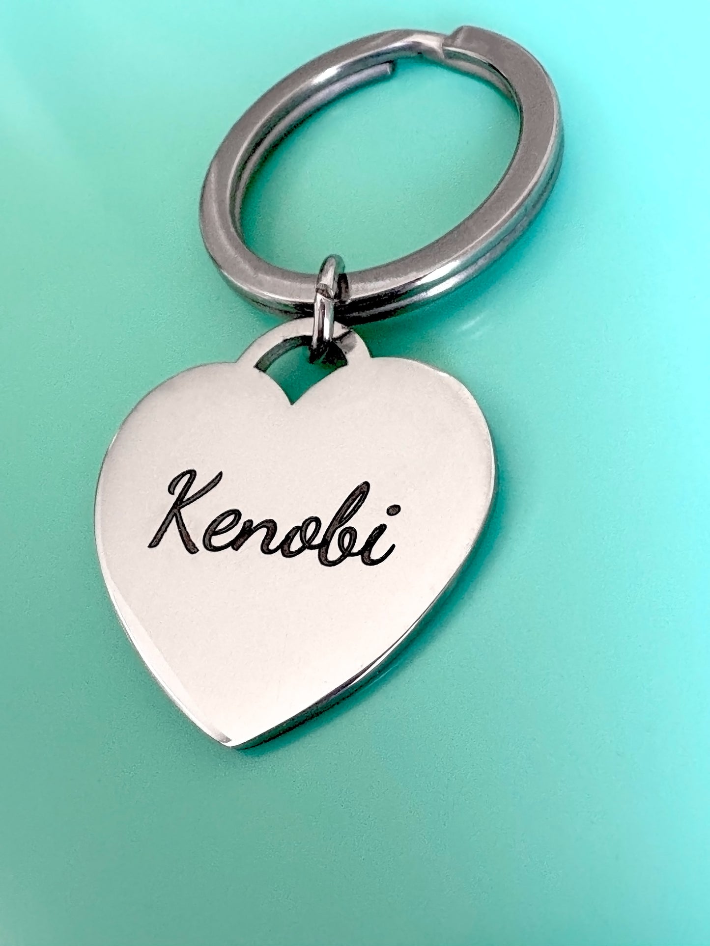 Heart-shaped keychain with a name engraving on a light blue background